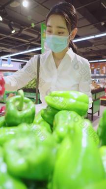 戴口罩的青年女人在<strong>超市</strong>选购蔬菜